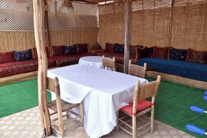 An outdoor seating area with a round table and chairs, a sofa, and a patterned wall.