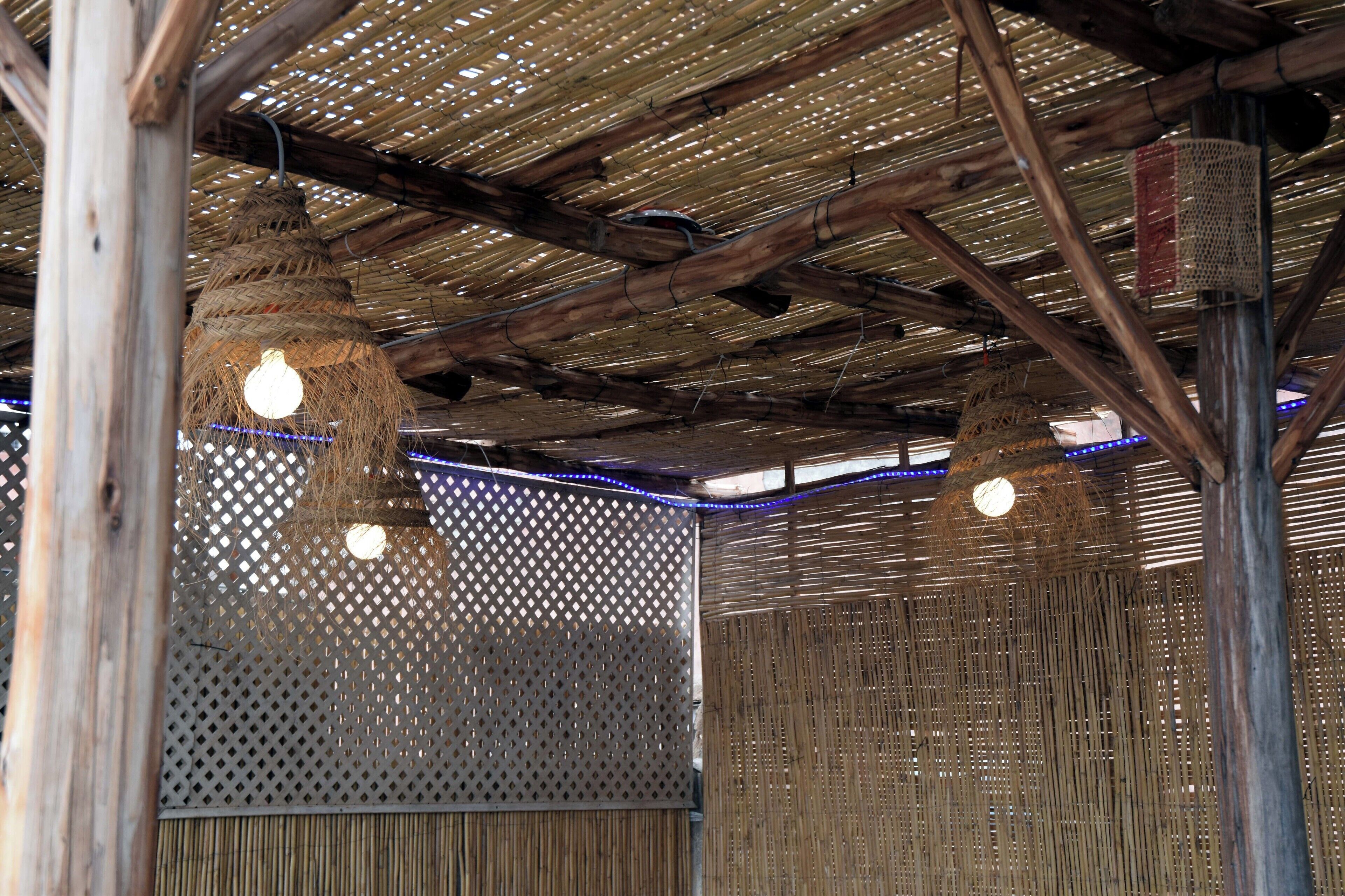 Ein rustikales Interieur mit Bambusdecken, gewobenen Wänden und hängenden Lampen.