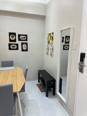A modern room with a wooden dining table, grey chairs, a black bench, and a mirror on the wall. - 1BR End Unit with 1.5 Bath, Private Balcony, Pool Access,Designated Free Parking (Metro Manila)