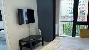 Une chambre d’hôtel moderne équipée d’un lit, d’une télévision, d’une petite table et d’un appareil de climatisation.
