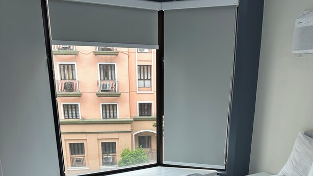 Une chambre d’hôtel avec une grande fenêtre, un lit recouvert de draps blancs et une serviette pliée en forme de cygne.