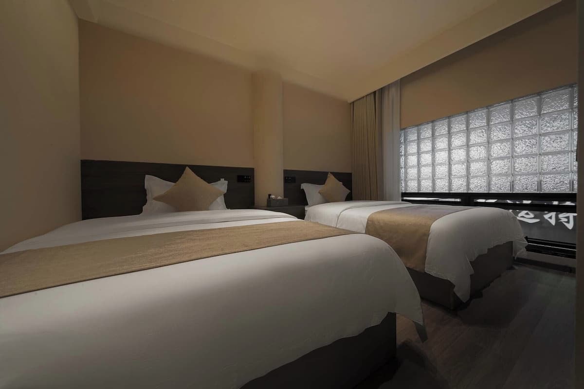 Een hotelkamer met twee bedden, een groot raam met uitzicht en een modern design.