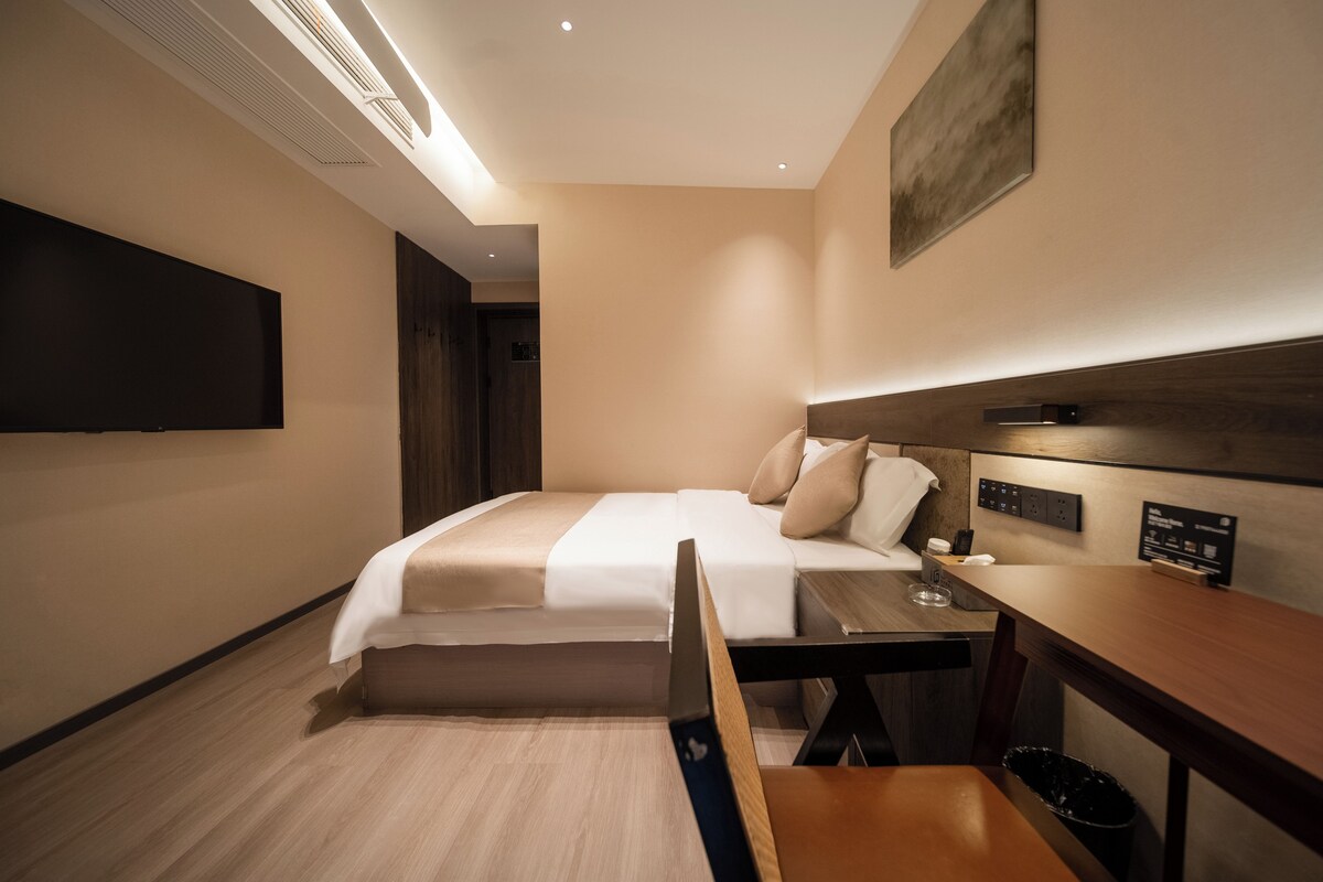 Une chambre d’hôtel avec un lit, une table de chevet et un bureau avec une chaise.