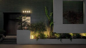 Une façade moderne d’un immeuble sur laquelle on peut lire l’inscription « 谷奈酒店 » (Yuan Nai Wine Shop).