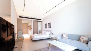 Moderni hotellihuone, jossa on sänky, sohva, sohvapöytä ja televisio.