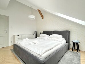 Ein modernes Schlafzimmer mit Bett, Nachttischen, einer Nachttischlampe und einer Hängelampe.