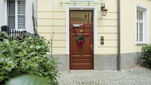 Ein gelbes Gebäude mit einer braunen Tür, einem kleinen Fenster und einem Briefkasten.