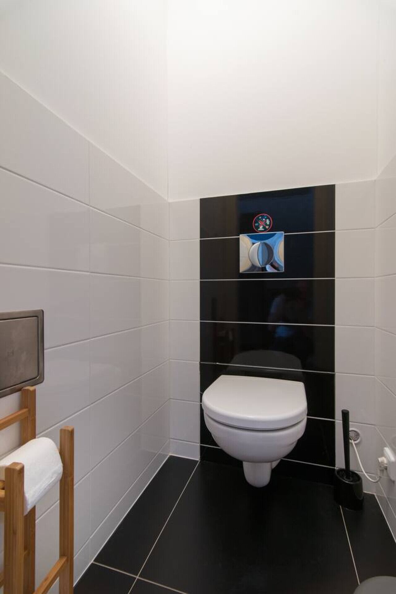 Ein modernes Badezimmer mit Toilette, schwarzen Fliesen und einem kleinen Bildschirm an der Wand.