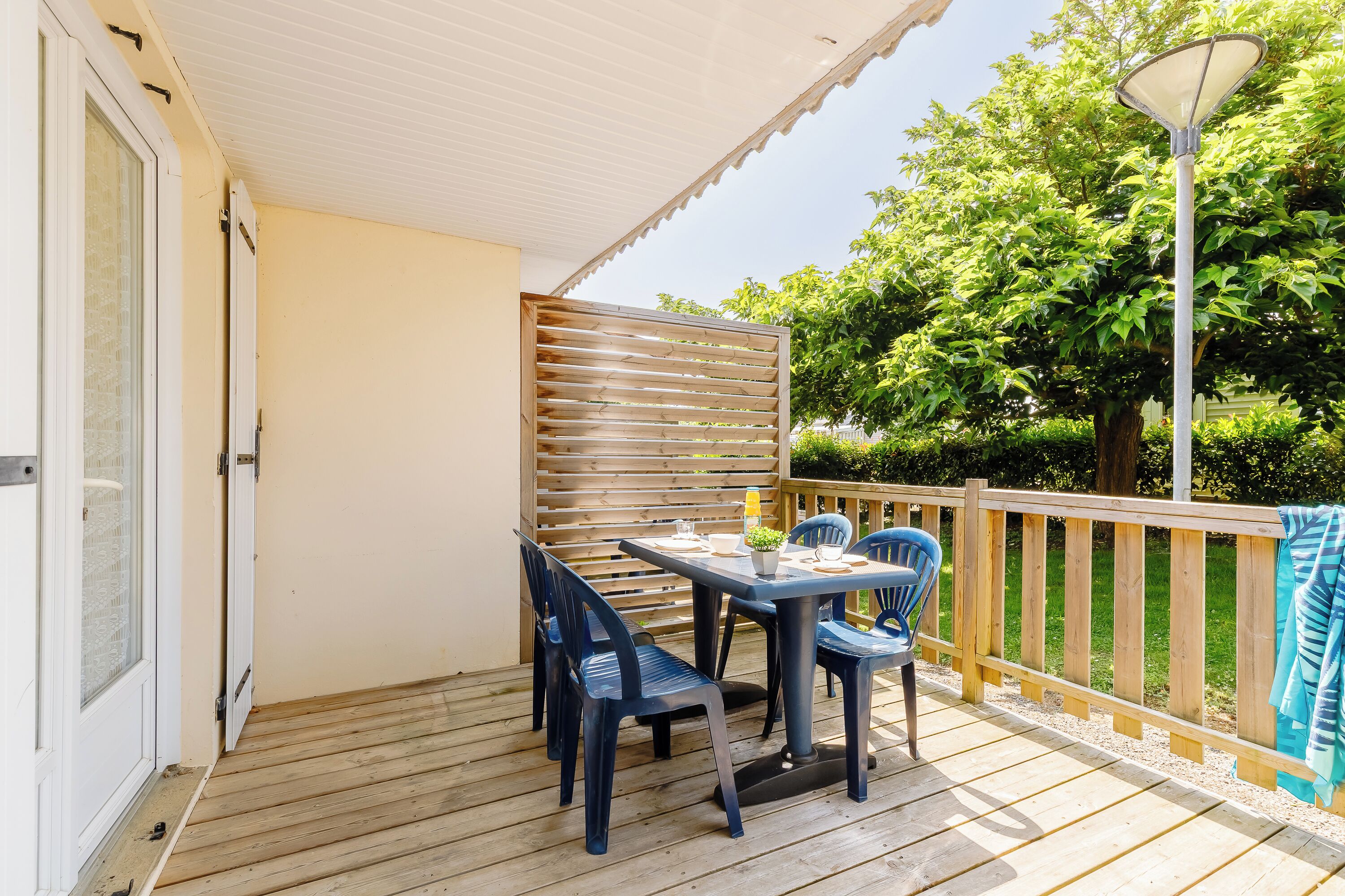 A wooden deck with a table and chairs, a wooden fence, and a lamp post.