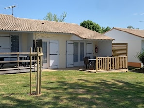 A two-story building with a tiled roof, a fenced patio area, and a small garden.