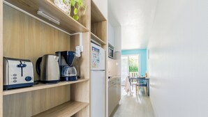 A modern kitchen with wooden shelves, a coffee maker, a toaster, and a refrigerator. - Village Vacances Gîtes Les Rivières (Maché)
