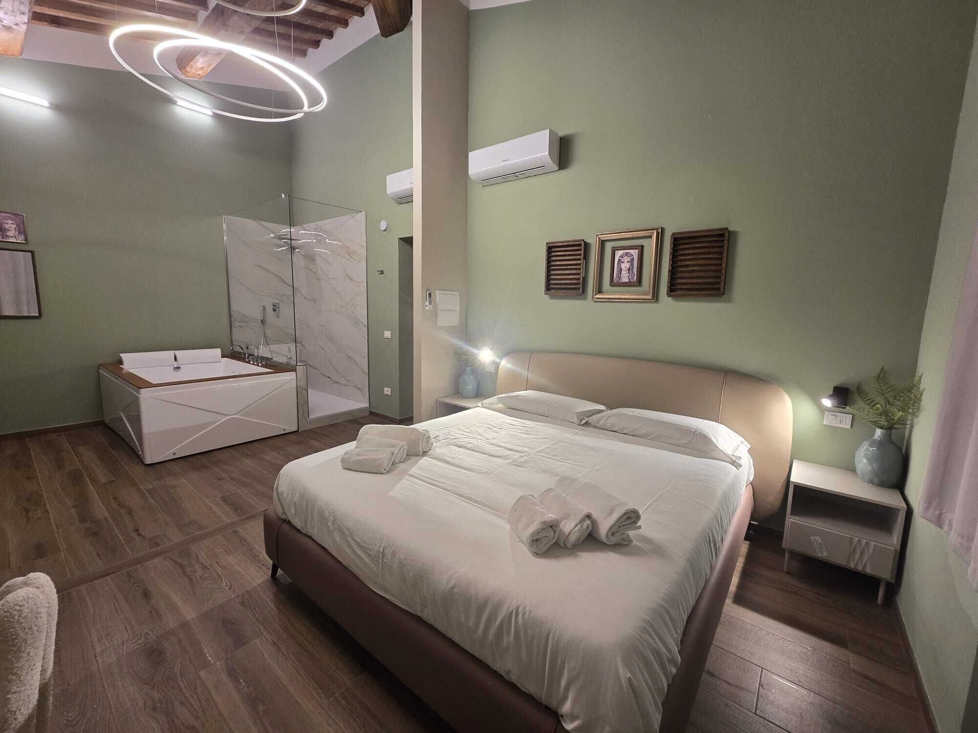 A modern bedroom with a large bed, a built-in bathtub, and a ceiling light fixture.