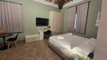A modern hotel room with a bed, desk, and television.