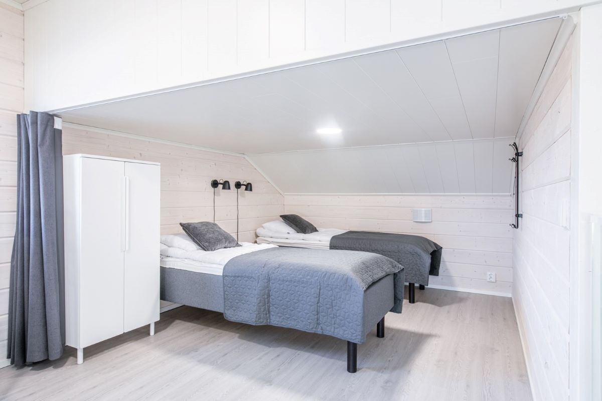 A compact bedroom with two beds, a wardrobe, and a ceiling fan.