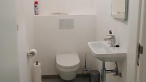 Un bagno piccolo e pulito, con il water, un lavandino e uno specchio.