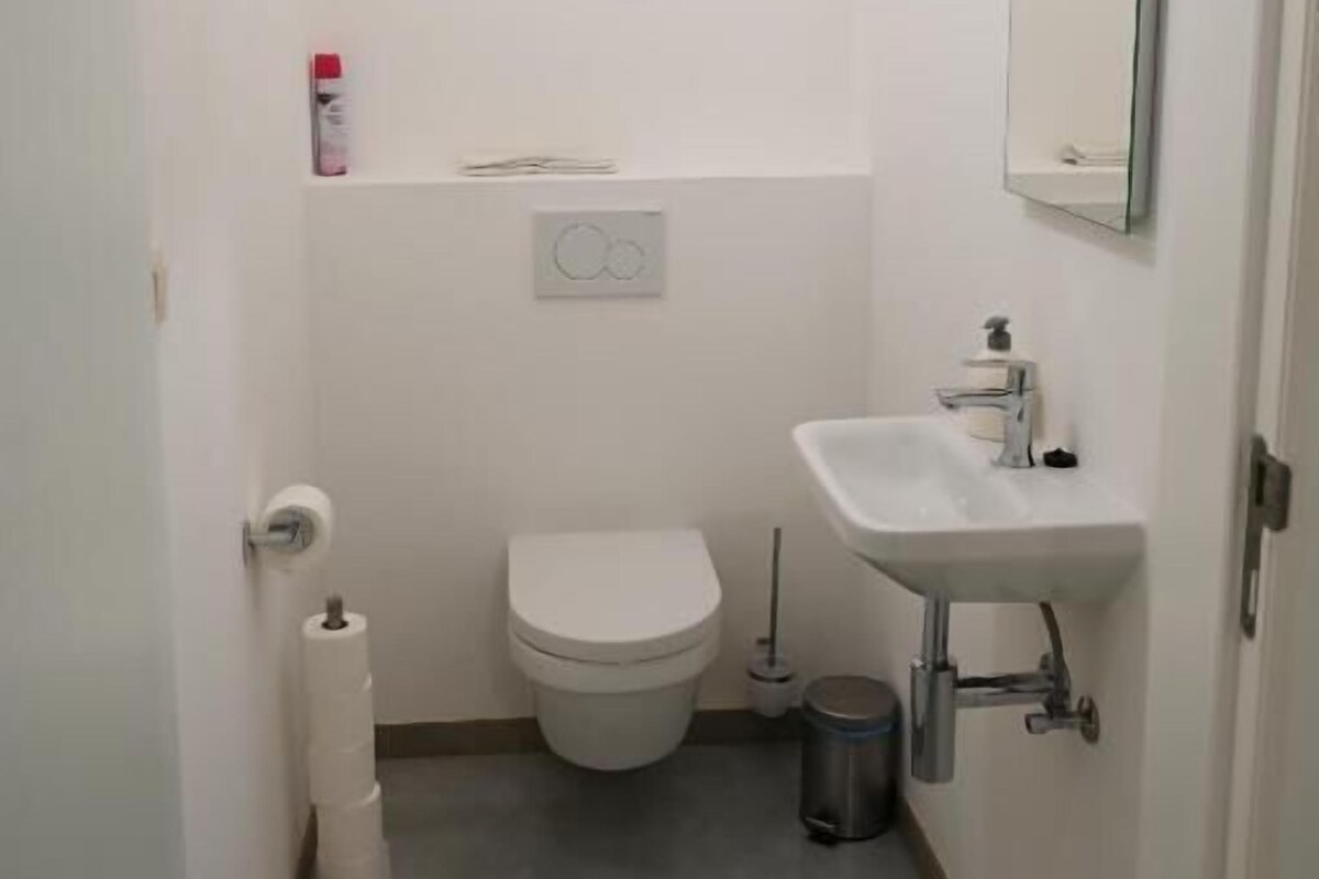 A small, clean bathroom with a toilet, sink, and mirror.