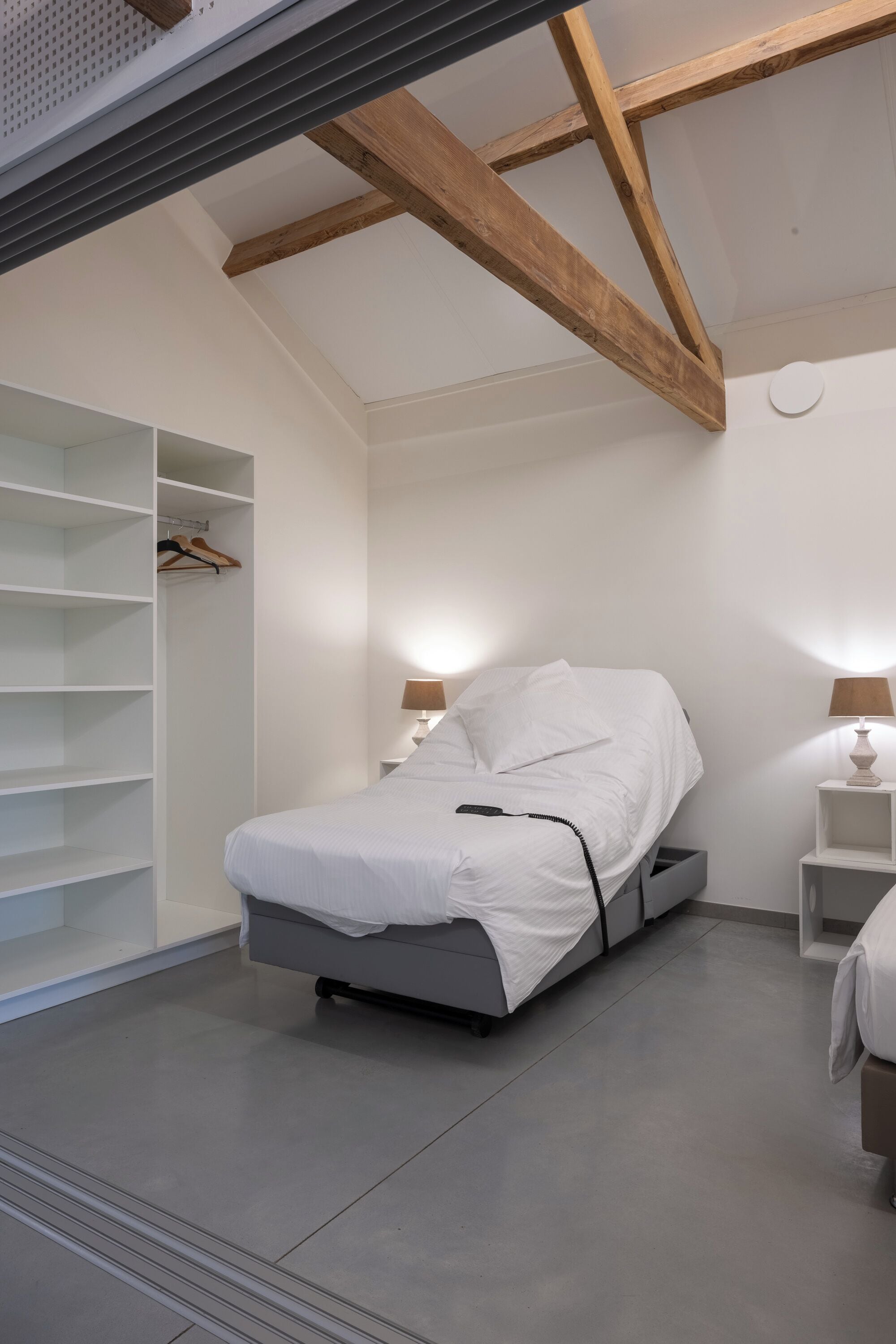 A modern bedroom with a bed, bedside tables, and built-in shelving.