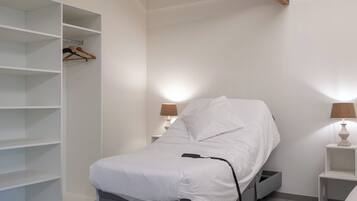 A modern bedroom with a bed, bedside tables, and built-in shelving.