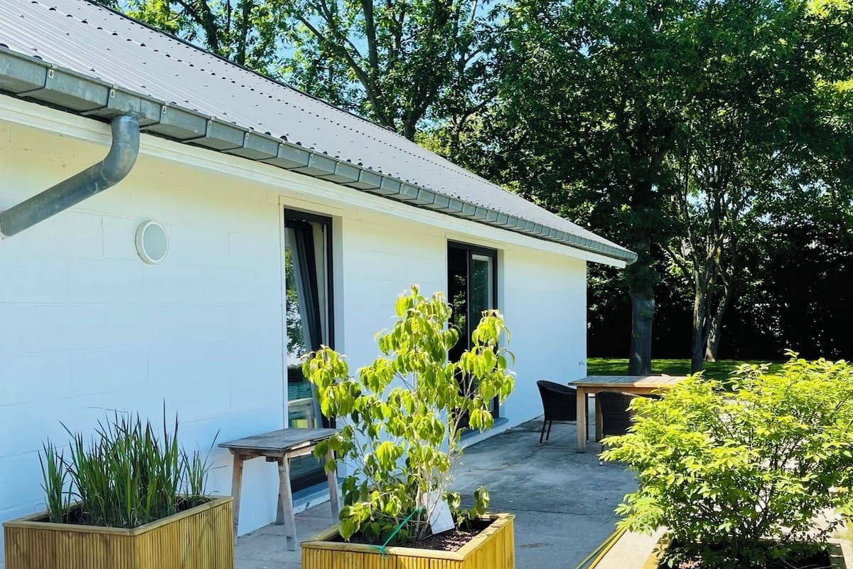 A building with a white exterior, a metal roof, and a small porch area with wooden planters containing green plants.
