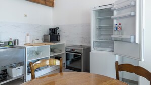 A compact kitchen with a refrigerator, microwave, toaster, and a wooden dining table. - Landlord  (Holsbeek)