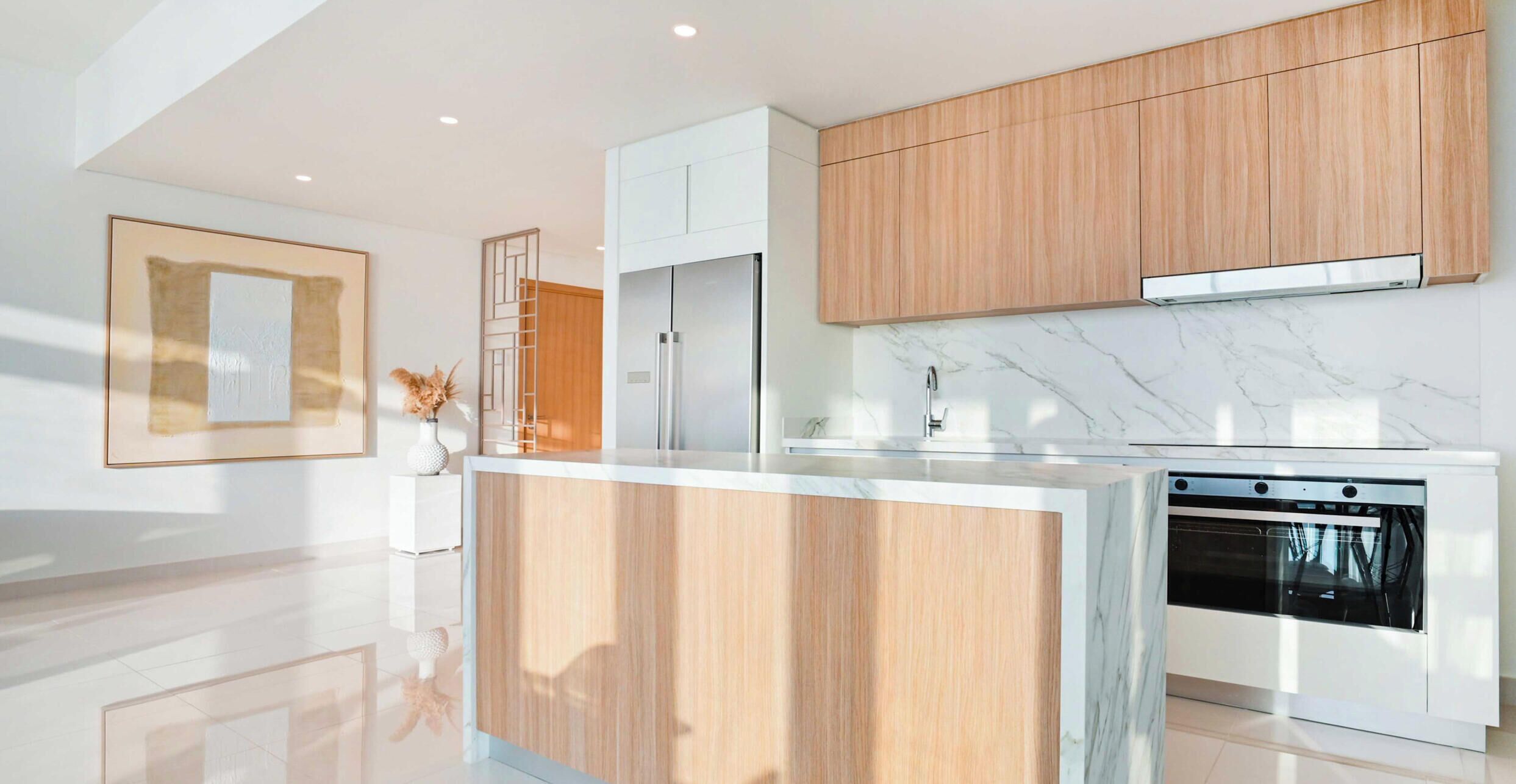 Une cuisine moderne avec des meubles en bois, un plan de travail en marbre et des appareils électroménagers en acier inoxydable.