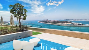 A rooftop pool area with a clear view of the sea and distant buildings. - LUX ULTRA Luxury Palm Dubai Eye Suite (Dubai)
