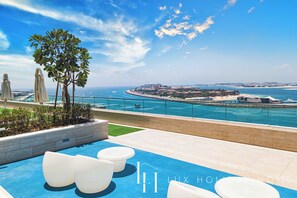 A rooftop pool area with a clear view of the sea and distant buildings. - LUX ULTRA Luxury Palm Dubai Eye Suite (Dubai)