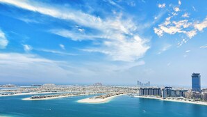 A coastal cityscape with a prominent tall skyscraper, a marina with boats, and a clear blue sky. - LUX ULTRA Luxury Palm Dubai Eye Suite (Dubai)