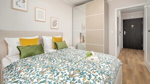 Een moderne slaapkamer met een groot bed, een kledingkast en een deur naar een andere kamer.