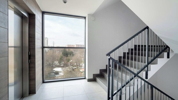 Een modern interieur met een groot raam, een trap en een deur naar een andere kamer.