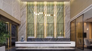 A reception area with a marble counter, modern lighting, and a large glass wall with vertical lines. - Hiatu Hotel   Huidong Huangbu Branch (Huizhou)