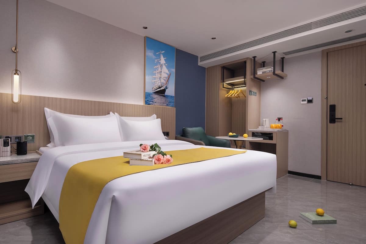 Quarto de hotel moderno com uma cama grande, uma escrivaninha e uma área de estar.