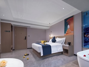 Quarto de hotel moderno com uma cama grande, uma mesa de cabeceira, um aparador e um banheiro com banheira, além de um grande mural na parede.