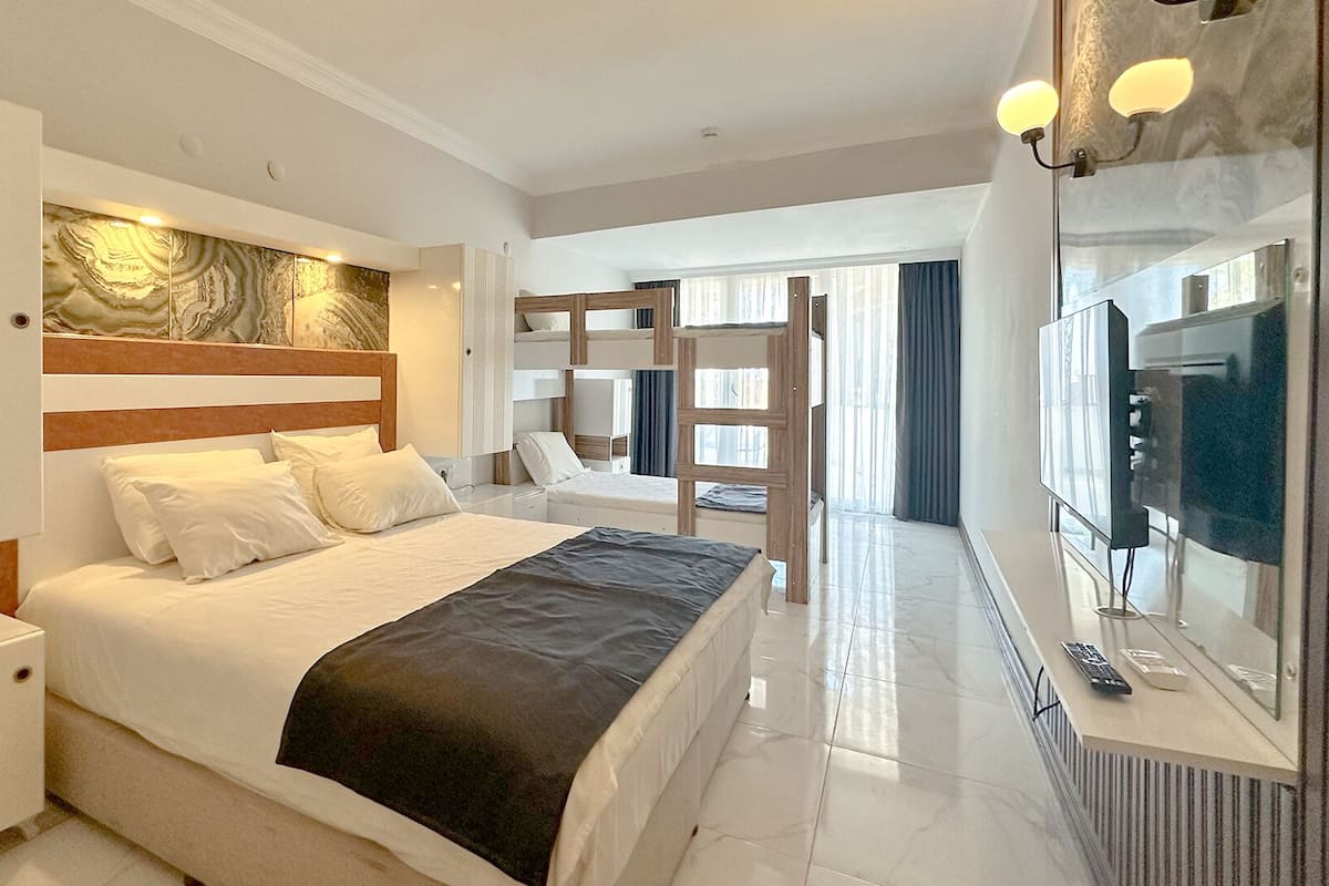 A hotel room with a bed, bedside table, TV, and a view of the city.