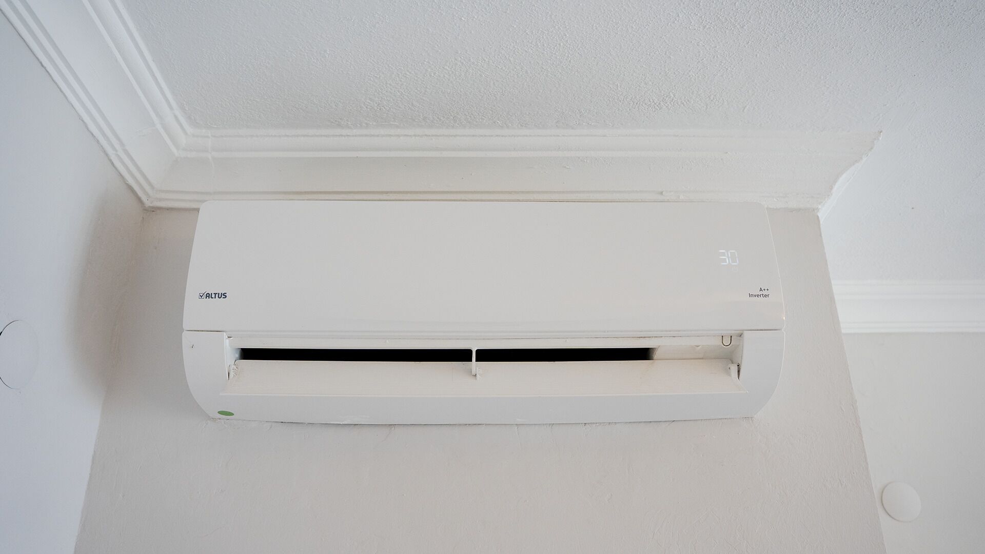 A white air conditioning unit mounted on a wall with a visible brand logo and model number.