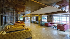 A spacious lobby with a marble floor, yellow and pink upholstered sofas, and large windows offering a view of the outdoors. - Veluna Beach Resort Yalikavak (Bodrum)