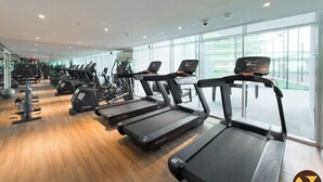 Ein modernes Fitnessstudio mit Laufbändern, Crosstrainern und Kurzhanteln.