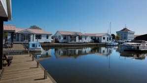 A marina with docked boats, a wooden pier, and several white buildings with red roofs. - Swift Cottage, Norfolk Broads riverside holiday rental with boat mooring (Potter Heigham)
