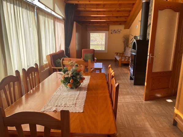 Un coin repas avec une table en bois, des chaises, un chemin de table en dentelle et un centre de table floral.