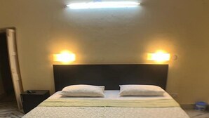 Habitación de hotel con cama, dos lámparas de noche, una mesita de noche y una lámpara de pared.