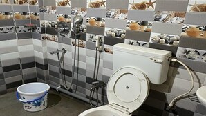 Un baño con inodoro, bidé y ducha. Las paredes están cubiertas de azulejos con un diseño de conchas marinas y estrellas de mar.