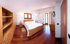A bedroom with a wooden bed, bedside tables, a wardrobe, and a desk with a chair. - Olga's Relais (Nerano)