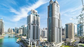 A high-rise hotel with multiple floors, a river in the foreground, and a clear blue sky. - LUX The Marina View Suite 2 (Dubai)