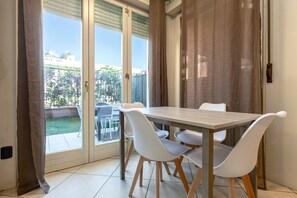 Et spiseområde med et bord og stole, en skydedør til en balkon og udsigt over det fri.