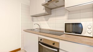 A kitchen with white cabinets, a microwave, a sink, and a wooden countertop. - Bright Studio Apartment with Private Garden (Bergamo)