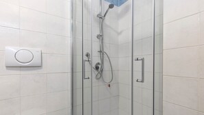 A glass-enclosed shower with a handheld showerhead and a wall-mounted control panel. - Bright Studio Apartment with Private Garden (Bergamo)