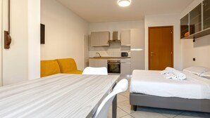 A compact bedroom with a bed, a small kitchenette, and a dining area. - Bright Studio Apartment with Private Garden (Bergamo)
