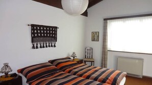 Un dormitorio con cama, un tapiz, una silla y una ventana.