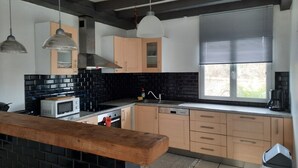 Eine moderne Küche mit schwarz-weißen Fliesen, Holzschränken, einer Mikrowelle und einer Kaffeemaschine.