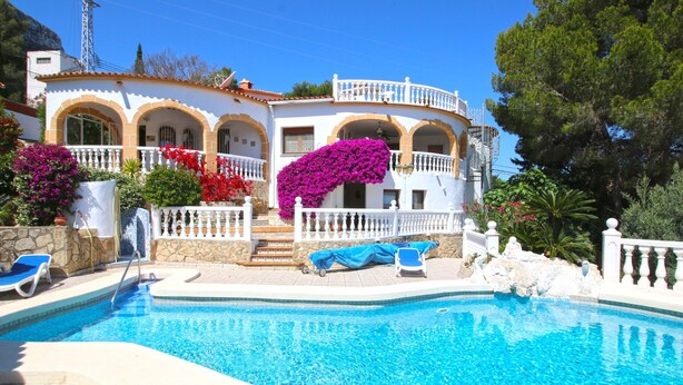 Ein Swimmingpool mit einem weißen Haus im Hintergrund.